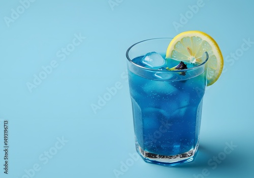 A refreshing blue drink garnished with a lemon slice on a blue background