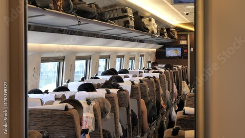 The concept of rail transit mobility, depicted by a rear-facing shot of passengers seated within a carriage on a speeding Chinese train.