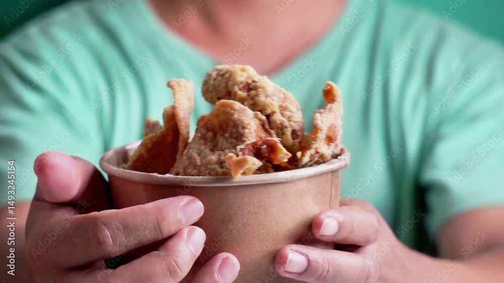 Keripik kulit ayam (Chicken skin chips) in a paper bowl. Indonesian street food.