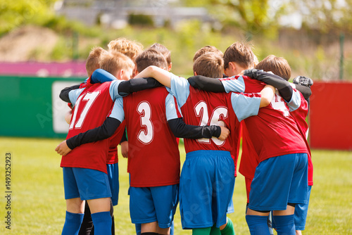 Fototapeta Naklejka Na Ścianę i Meble -  Young Soccer Team in Red Jerseys Huddles Together Before a Match on a Sunny Day, Showing Team Spirit and Unity