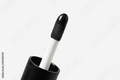 Close-up of black lip gloss applicator with glossy texture against bright white background