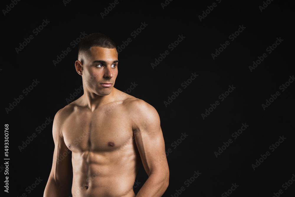 Shirtless fit man looking sideways with defined abs against black background. Lifestyle. Sport. Shirtless fit man looking sideways with defined abs against black background. Lifestyle. Sport.