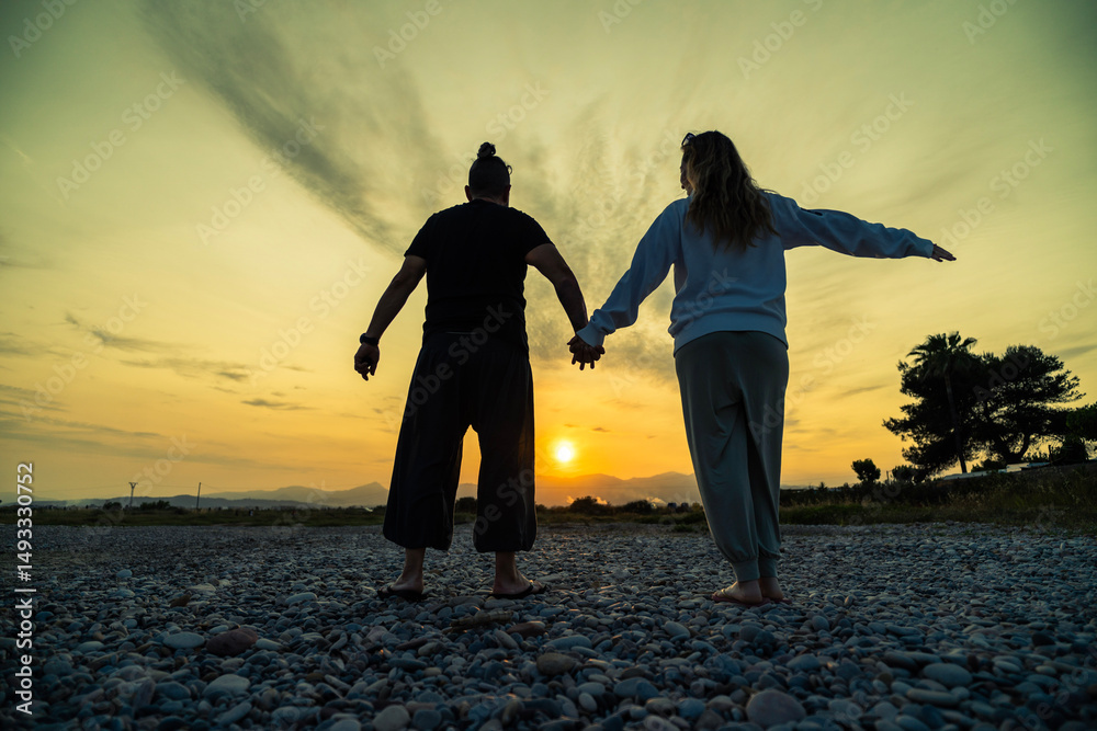 Fototapeta premium Couple enjoying sunset on rocky beach