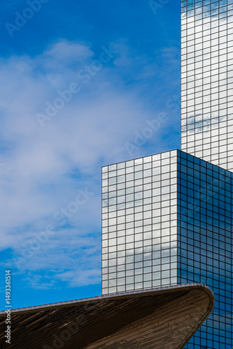 Modern skyscraper with reflective glass facade against blue sky, featuring geometric lines and clean design for use in business, architecture and urban development themes.