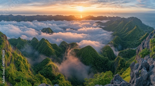 Majestic sunrise over a mountain range shrouded in clouds. Lush, green peaks pierce the mist