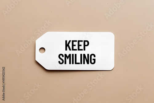 Top view of word keep smiling written on white tag on empty pastel background. Close up.
