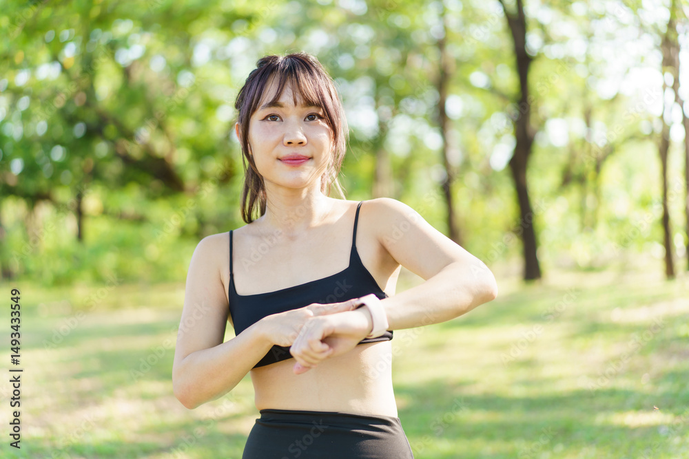 Fototapeta premium Asian woman using smartwatch or tracker to track her workout progress.