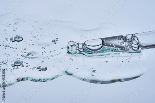 Pipette with a drop of hyaluronic serum on a blue background.