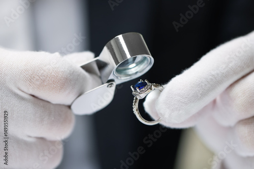Appraiser with loupe evaluating luxury ring, closeup photo