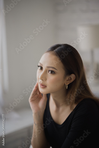 Thoughtful Young Woman with Subtle Makeup in a Black Top