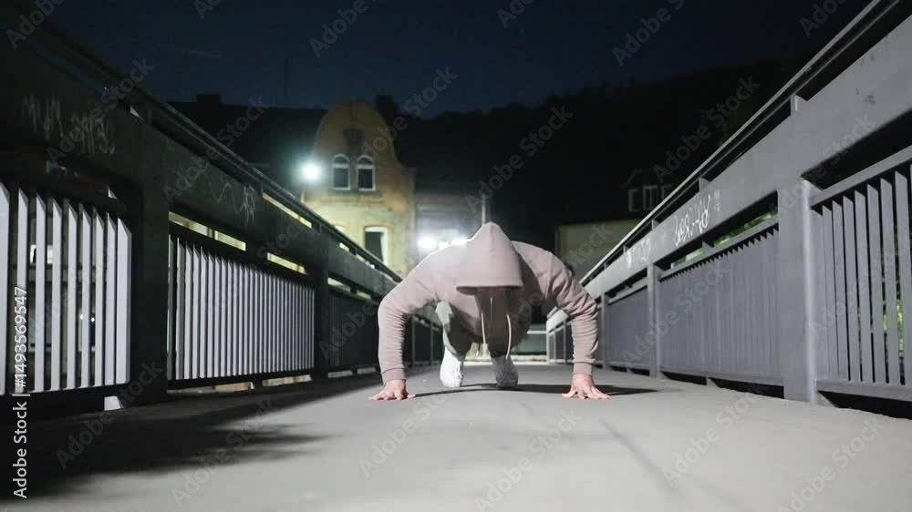 A person performs push-ups on a dimly lit bridge during nighttime, showcasing fitness and determination.