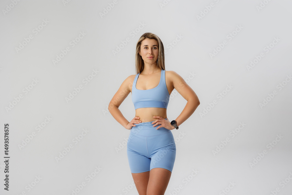Obraz premium Fitness enthusiast poses confidently in light blue athletic wear for a stylish indoor workout session