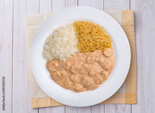 Shrimp strogonoff with rice and straw potato over wooden table