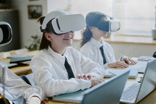 Students with VR headsets sitting in classroom, engaging in immersive technology. They appear focused and enthusiastic while experiencing virtual learning environment