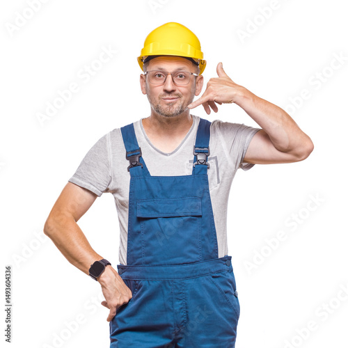 Call me, construction worker gesturing at speaking on phone while looking to camera, isolated on white background. Middle-aged construction worker on phone. Craftsman against white wall