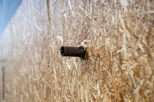 Metal pipe penetrating through a chipboard (DSP) plane, showcasing industrial force or accidental damage