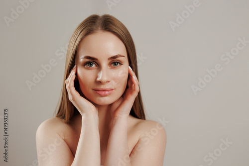 Beauty and serenity captured in a close-up portrait of a woman with long hair and natural makeup in a soft-toned setting