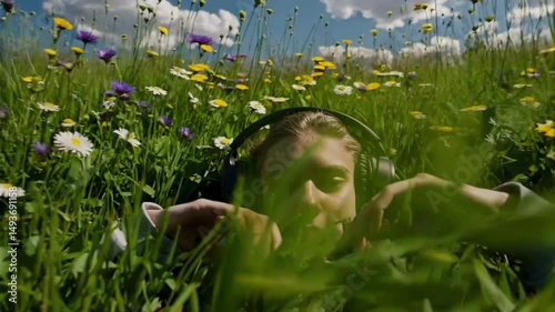 Person with headphones relaxing in wildflower field