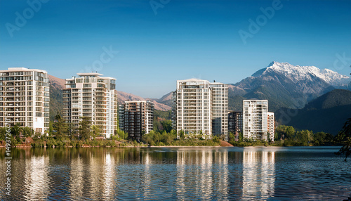 View of modern apartment buildings seen from a beautiful lake with mountains in the background
