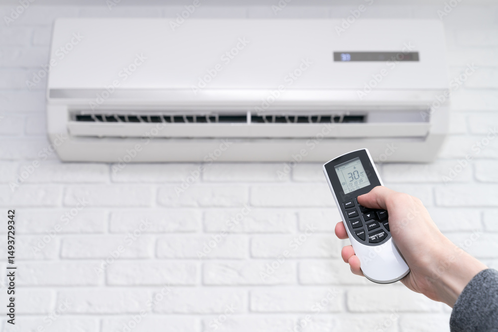 Fototapeta premium Air conditioner temperature adjustment with remote controller in room at home.