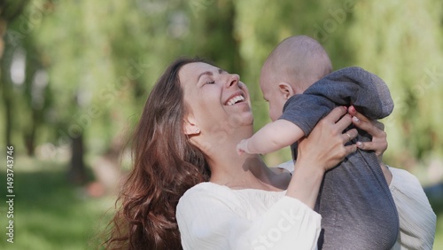 A beautiful joyful and happy mother with a small child in her arms summer portrait