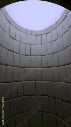 Low-angle, wide view of an arched chamber featuring soft, padded rectangular panels lining the walls and ceiling. A bright opening at the apex illuminates the interior of this unique, insulated