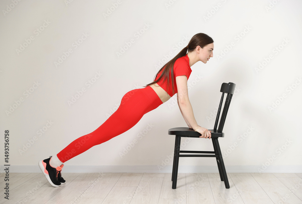 Obraz premium Beautiful woman exercising with chair at home