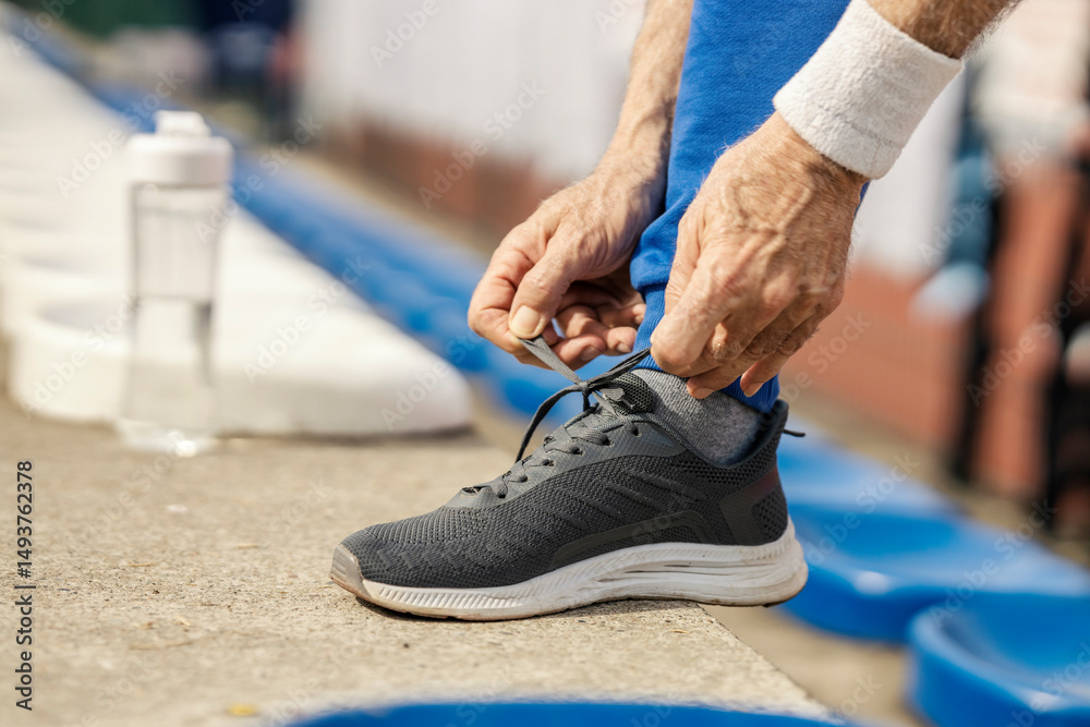 Fototapeta premium Close up of senior sportsman tying shoelace.