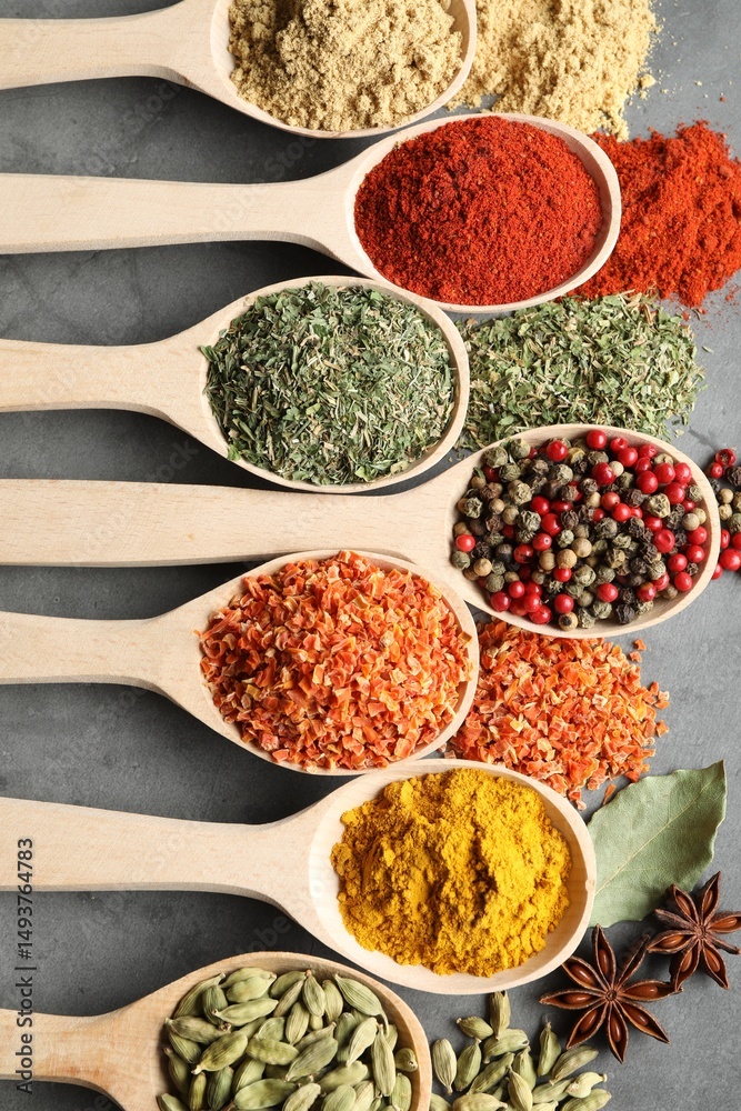 Many different spices in spoons on grey table, flat lay Many different spices in spoons on grey table, flat lay