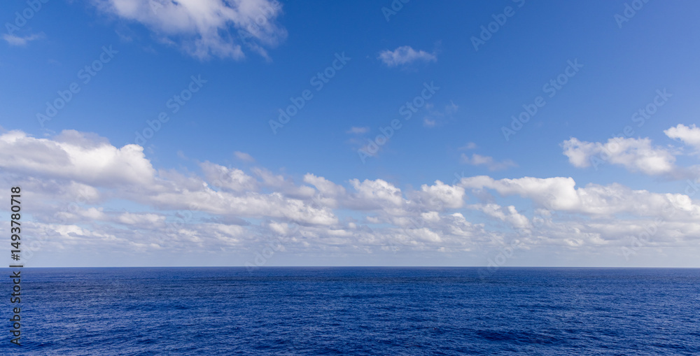 Obraz premium Blue Ocean Horizon Under a Vibrant Sky with White Clouds