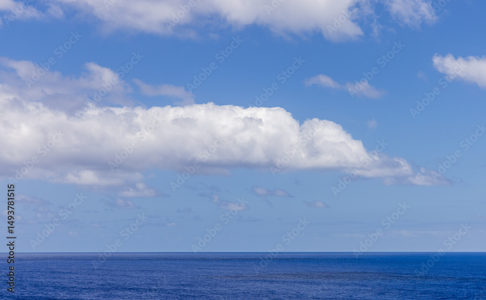Obraz premium Blue Sky Over Calm Ocean with Large Fluffy White Clouds