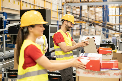 Warehouse workers are focused on organizing boxes, emphasizing teamwork and the importance of efficient logistics.