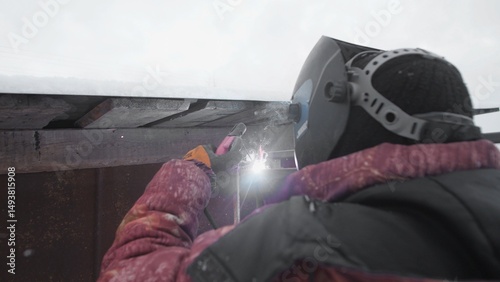 A skilled welder is working carefully in the snow, showcasing winter safety measures and excellent craftsmanship