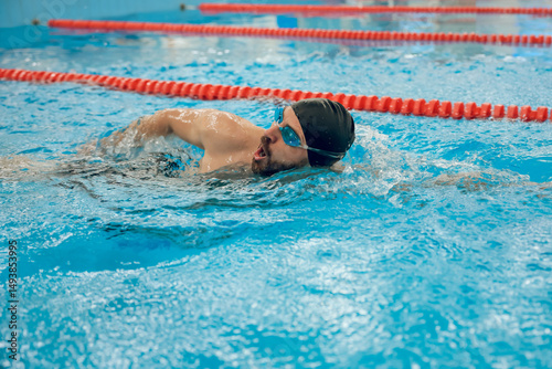 Man in black swimming cap swimming crawl style in the pool