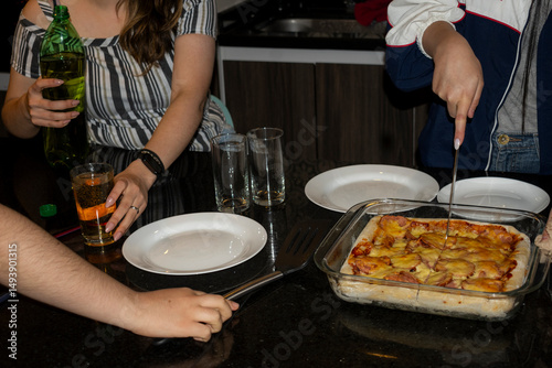 Unrecognizable people serving a meal in a modern kitchen, showcasing culinary teamwork, leisure, and friendship.