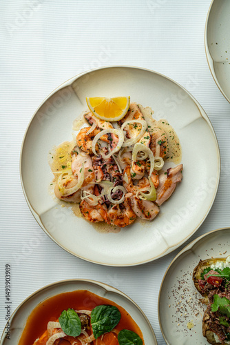 A beautifully presented seafood dish showcases succulent morsels topped with fragrant herbs and fresh onion slices. The colorful plate is garnished, inviting guests to indulge in a culinary delight