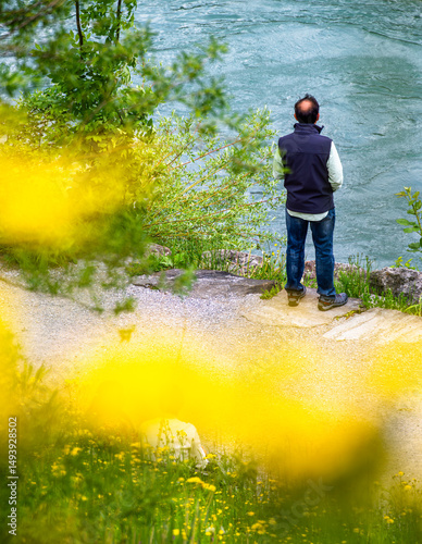 Man Contemplating by the River with Wildflowers