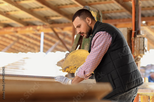 Young carpenter sawing wood...