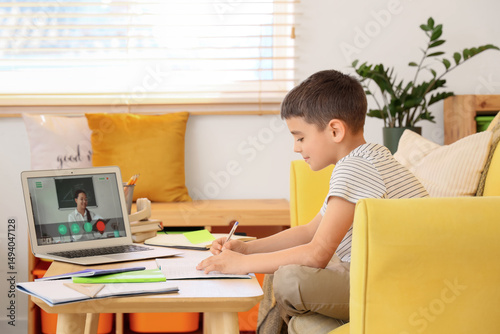 Little boy with laptop studying online at home