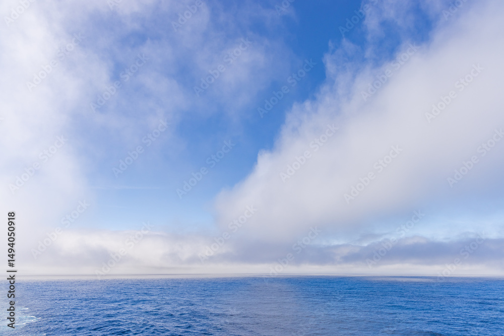 Fototapeta premium Serene Ocean Scene With Blue Sky and Fluffy Cloud Formations