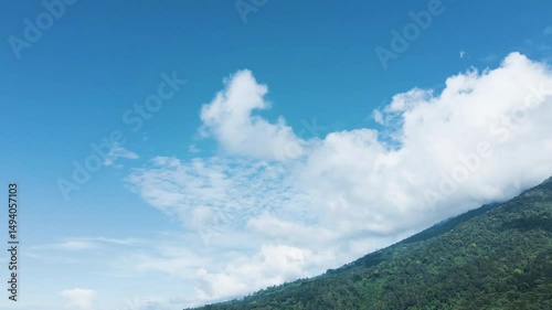 4K Drone Flyover of Cloudy Green Mountain with Clear Sky

