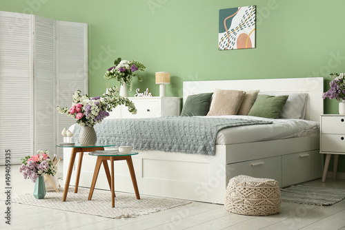 Interior of bedroom with comfortable bed and beautiful flowers