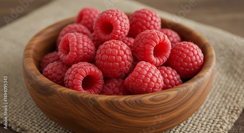 A close-up of a bunch of fresh raspberries in a wooden bowl placed on a linen napkin The raspberries' texture and the bowl's wood grain are visible
