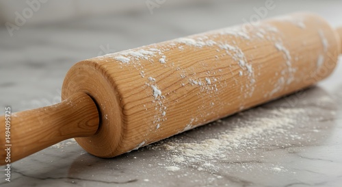 A close-up photo of a wooden rolling pin dusted with flour resting on a marble countertop The rolling pin's texture and the flour details are in sharp focus