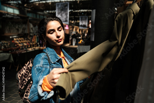 Photography Young woman choosing clothes in vintage shop at flea market