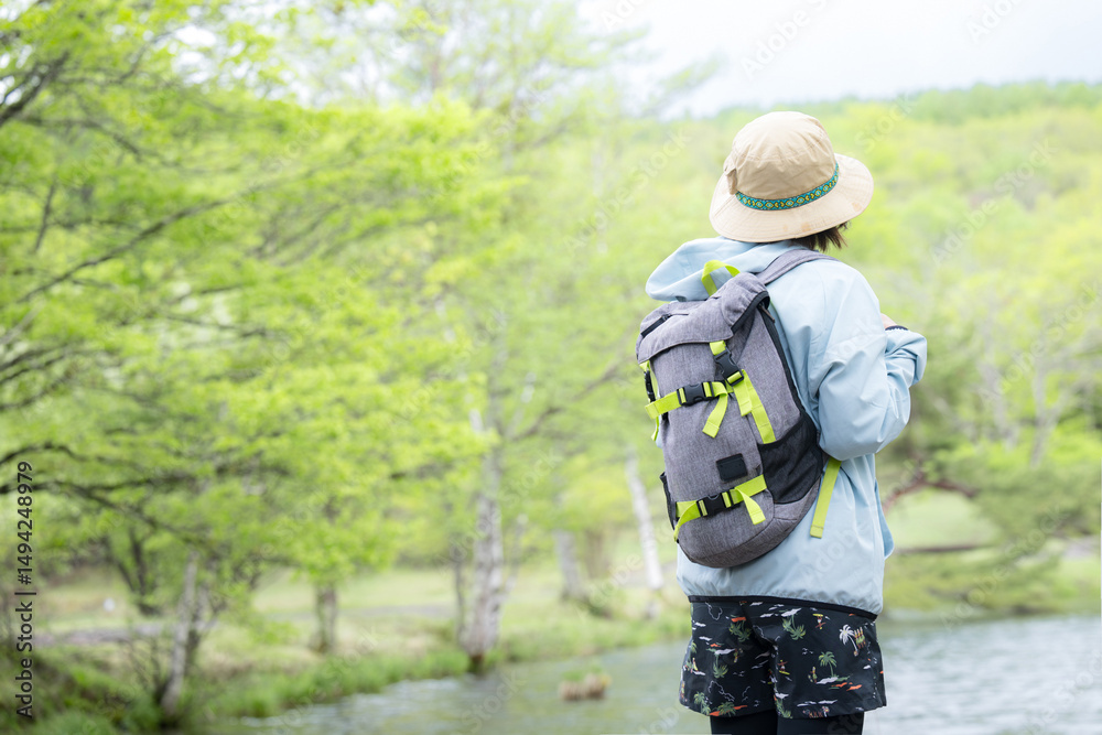 Naklejka premium 登山やトレッキングをする人 湖や景色を眺める顔無しの後ろ姿の女性 左にコピースペースあり
