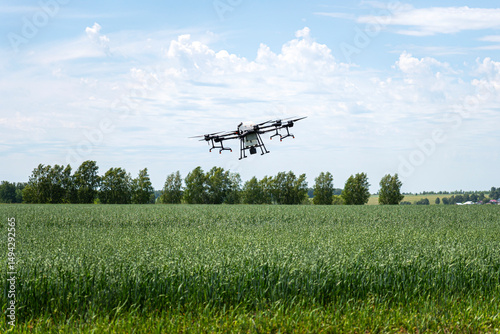 An industrial drone in the sky. Drone sprayer flies over the agricultural field. Smart farming and precision agriculture. Quadrocopter for pollination of plants.