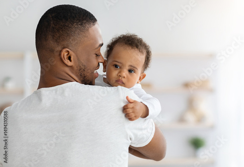Father's love. Young afrian american dad holding his sweet infant baby in hands, closeup shot of caring black millenial dad spending time with cute adorable toddler child at home, copy space photo