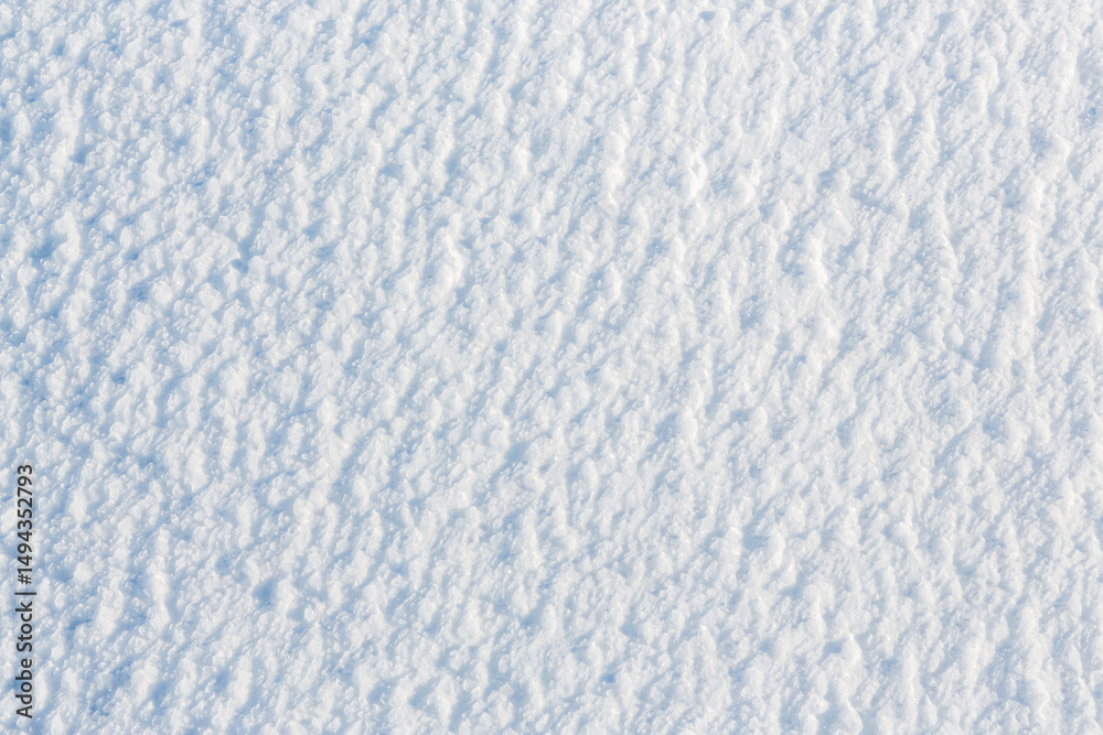 Fototapeta premium Natural snow texture. The surface of an icy snow crust. Snowy ground. Winter background with snow patterns. Perfect for Christmas and New Year design. Closeup top view.