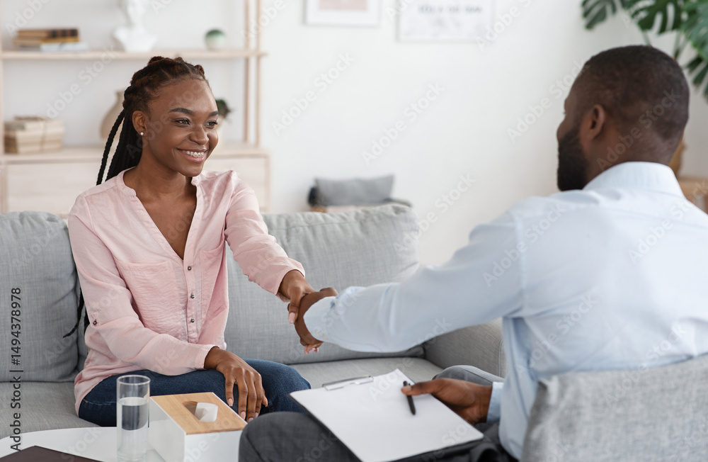 Fototapeta premium Nice To Meet You. Black male therapist meeting woman for counselling session, greeting each other with handshake, selective focus, free space
